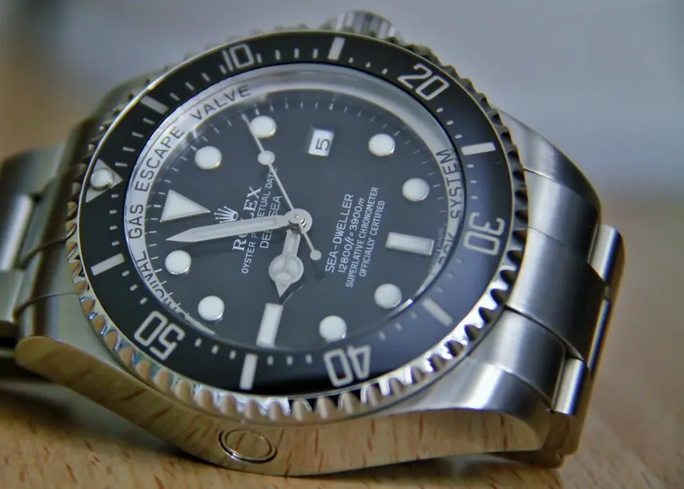 Stainless steel Rolex Sea-Dweller Deepsea ref. 116660 shot from a low angle on pale wood — stand-in photograph